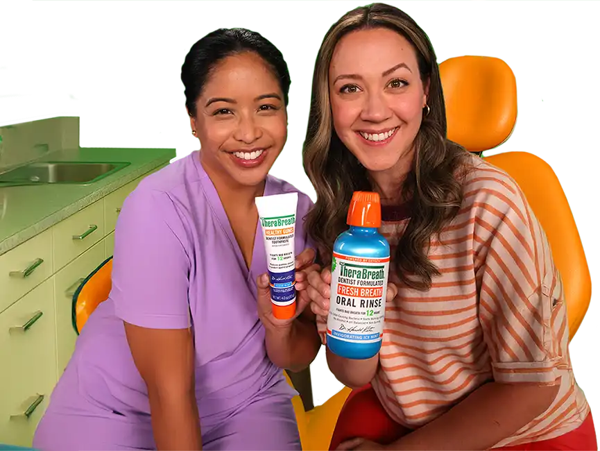 A dental hygienist and a patient seated in a dental office holding TheraBreath&trade; toothpaste and Fresh Breath oral rinse